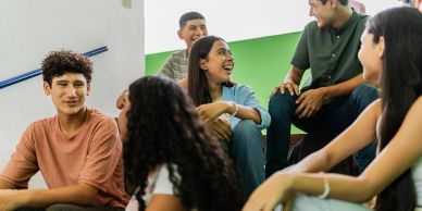 Group of young people talking and smiling indoors.