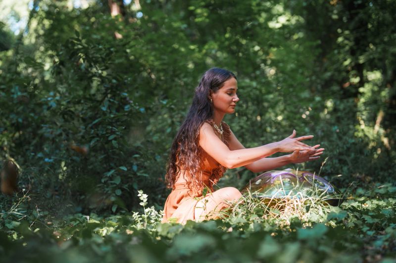 Environmentalist woman playing handpan in forest