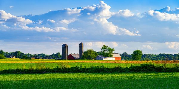 A serene farm with silos under a blue sky with clouds.