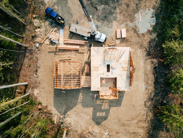 Aerial view of a house under construction with a crane and truck nearby.