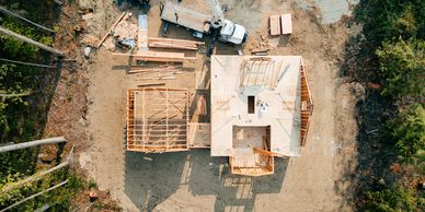 Aerial view of a house under construction with a crane and truck nearby.