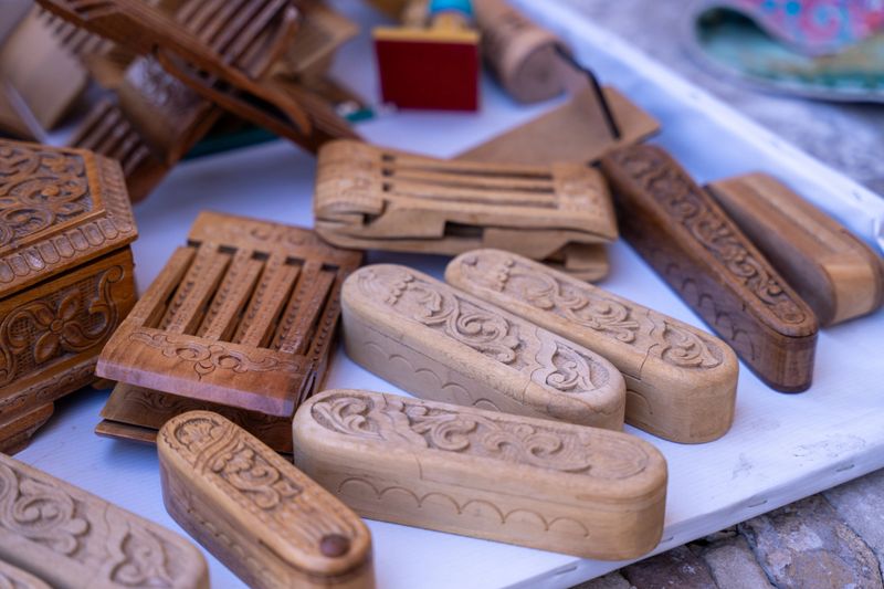 A collection of wooden boxes with intricate carvings on them. The boxes are arranged on a white surface