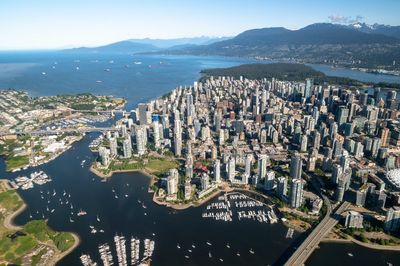 Photo of Vancouver from above showing mountains, water, bridges, and the city buildings.