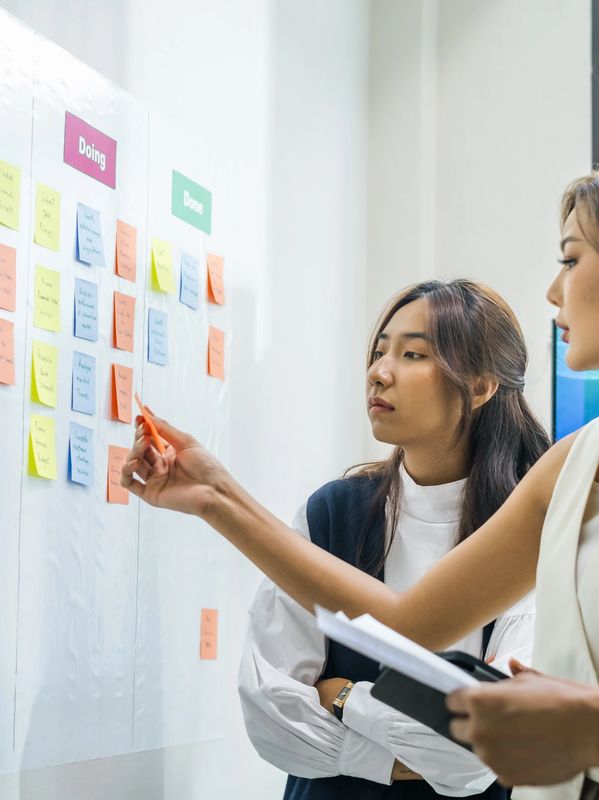 Three colleagues collaborating and organizing tasks on a sticky note board.