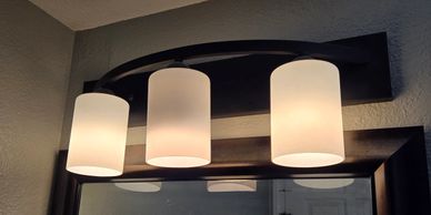 Three modern ceiling lights with frosted glass shades above a mirror.