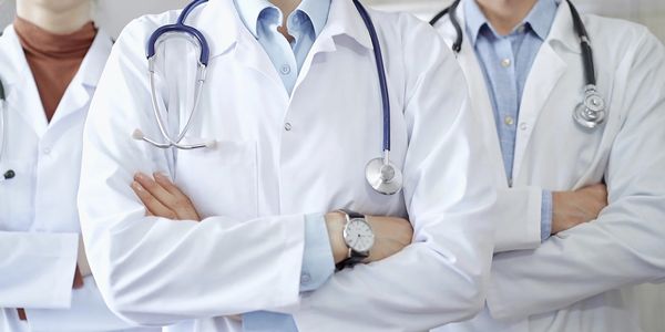 Doctors in white coats with stethoscopes standing with arms crossed.