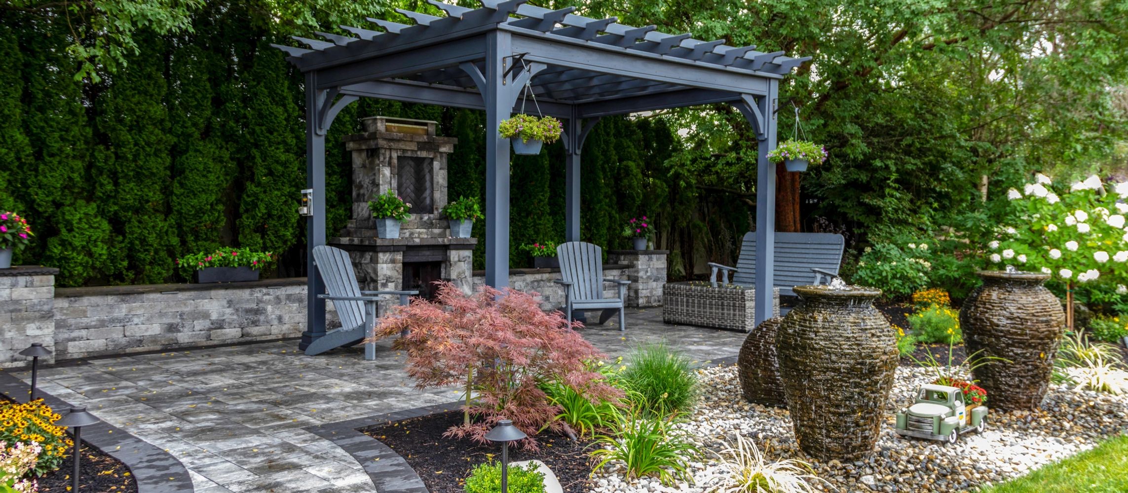 A serene backyard patio with a pergola, fireplace, and garden decor.