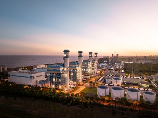 A large industrial power plant near a body of water at sunset.