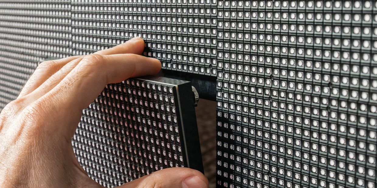 Hand installing a panel on a large LED display screen.