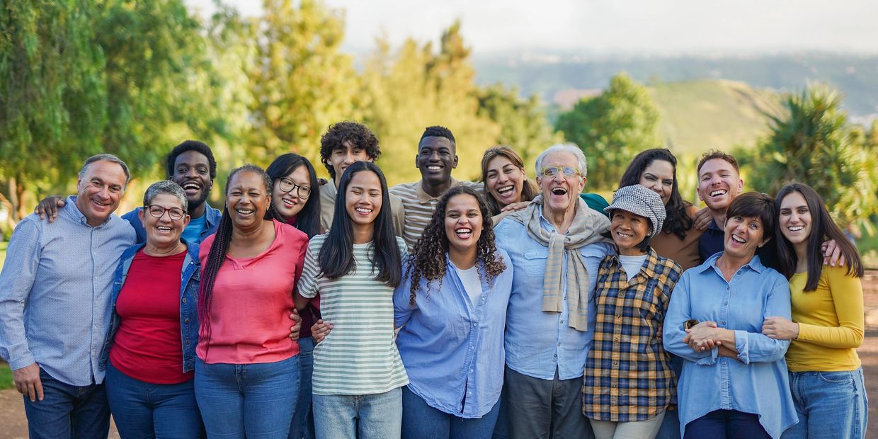 A diverse group of people smiling together outdoors, showing unity and happiness.