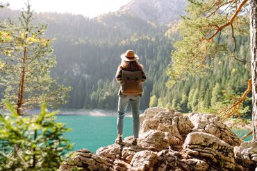 A person standing on top of rocks looking at the water.