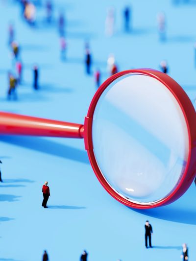 shows a huge magnifying glass with very small people around it