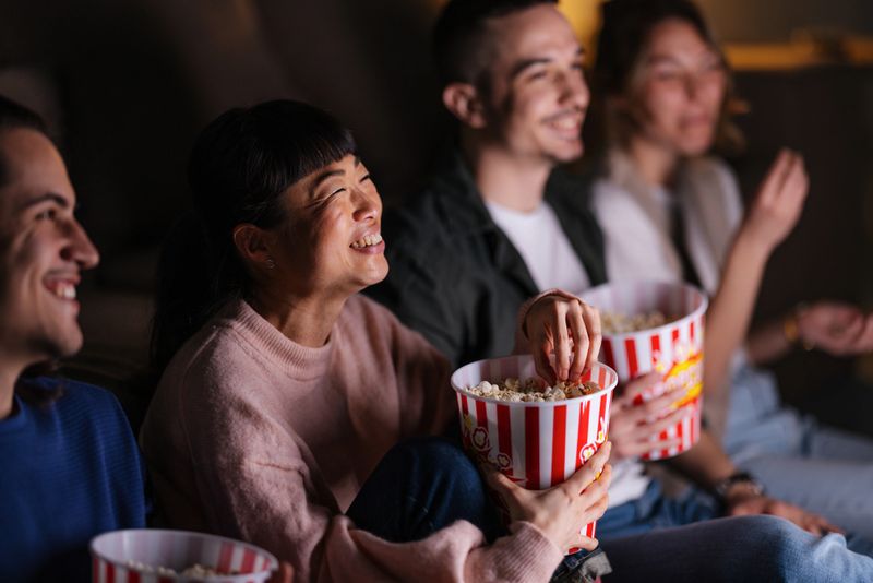 A joyful group of friends spending a fun movie night together, sharing smiles and popcorn while watching a film.