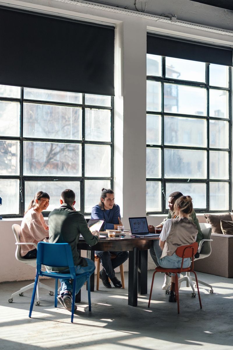 A group of young professionals working together in a bright, modern office space, collaborating on projects and exchanging ideas.