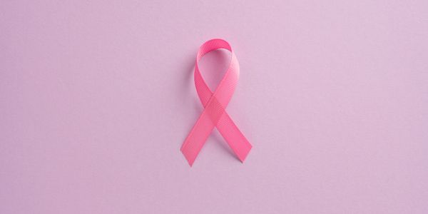 A pink ribbon symbolizing breast cancer awareness on a soft pink background.