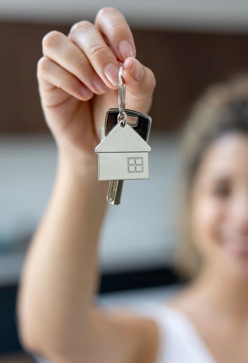 Close-up on a woman buying a house and holding her keys - home ownership concepts