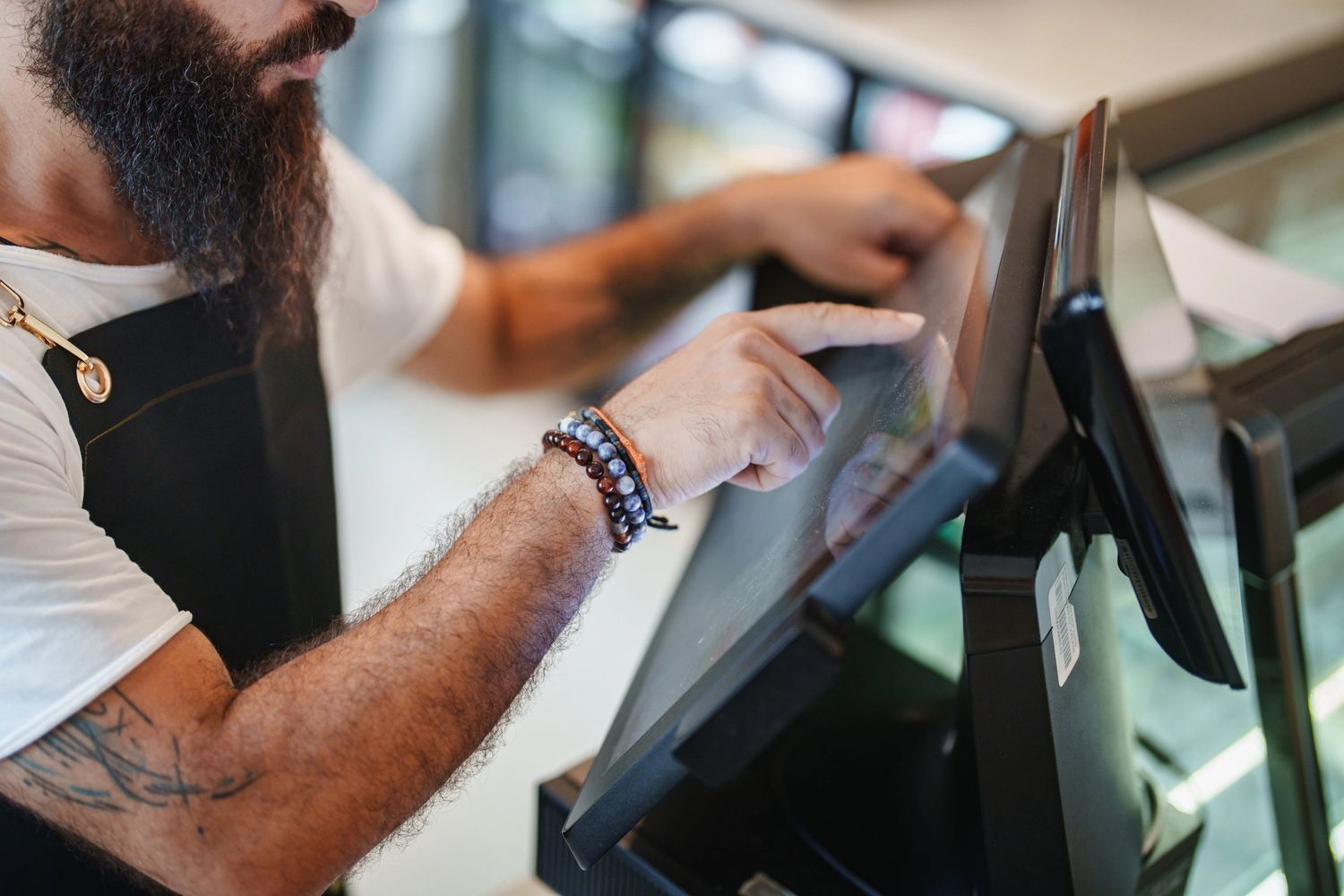 Bearded man using a touchscreen point-of-sale system.