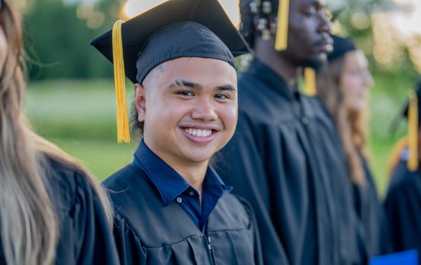 Smiling graduate in cap and gown at ceremony.