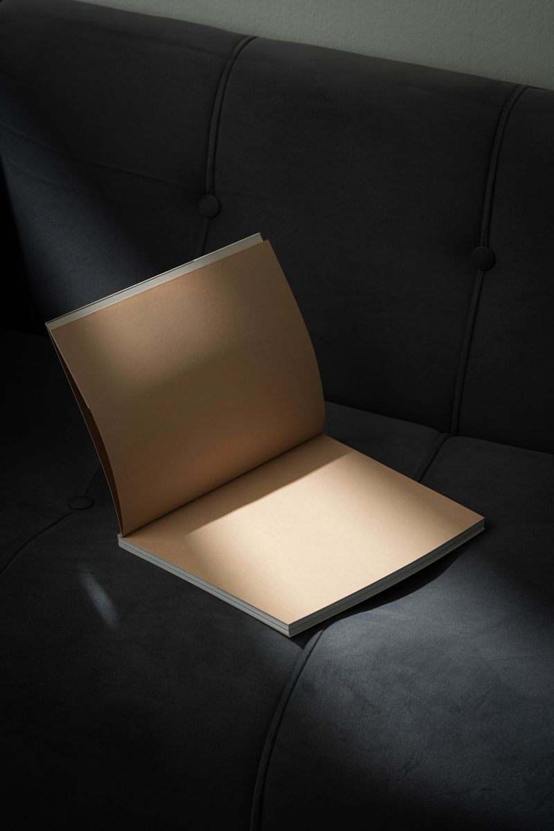 Stack of Magazines on a Black Leather Couch in Soft Light close up