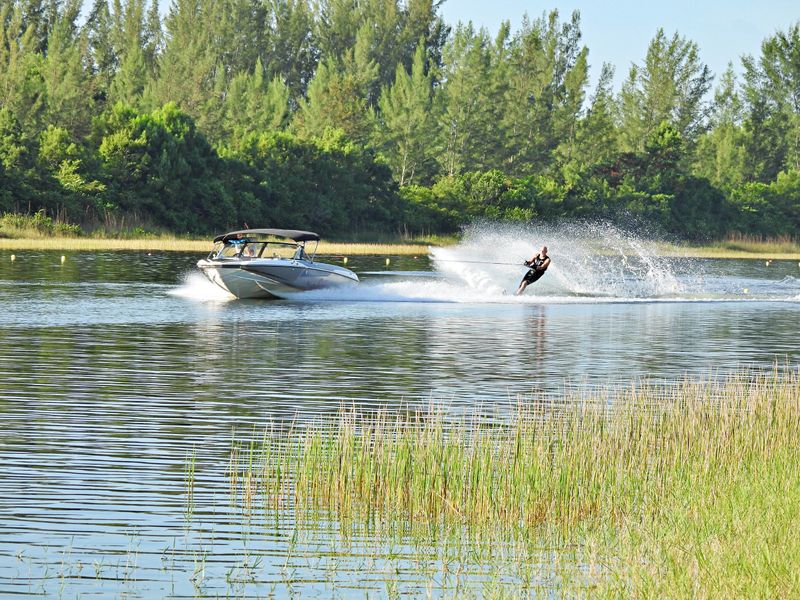 Skilled male waterskiing on a lake with splashing.