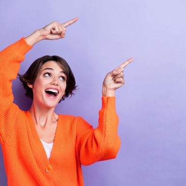 Happy woman in orange sweater pointing up excitedly.