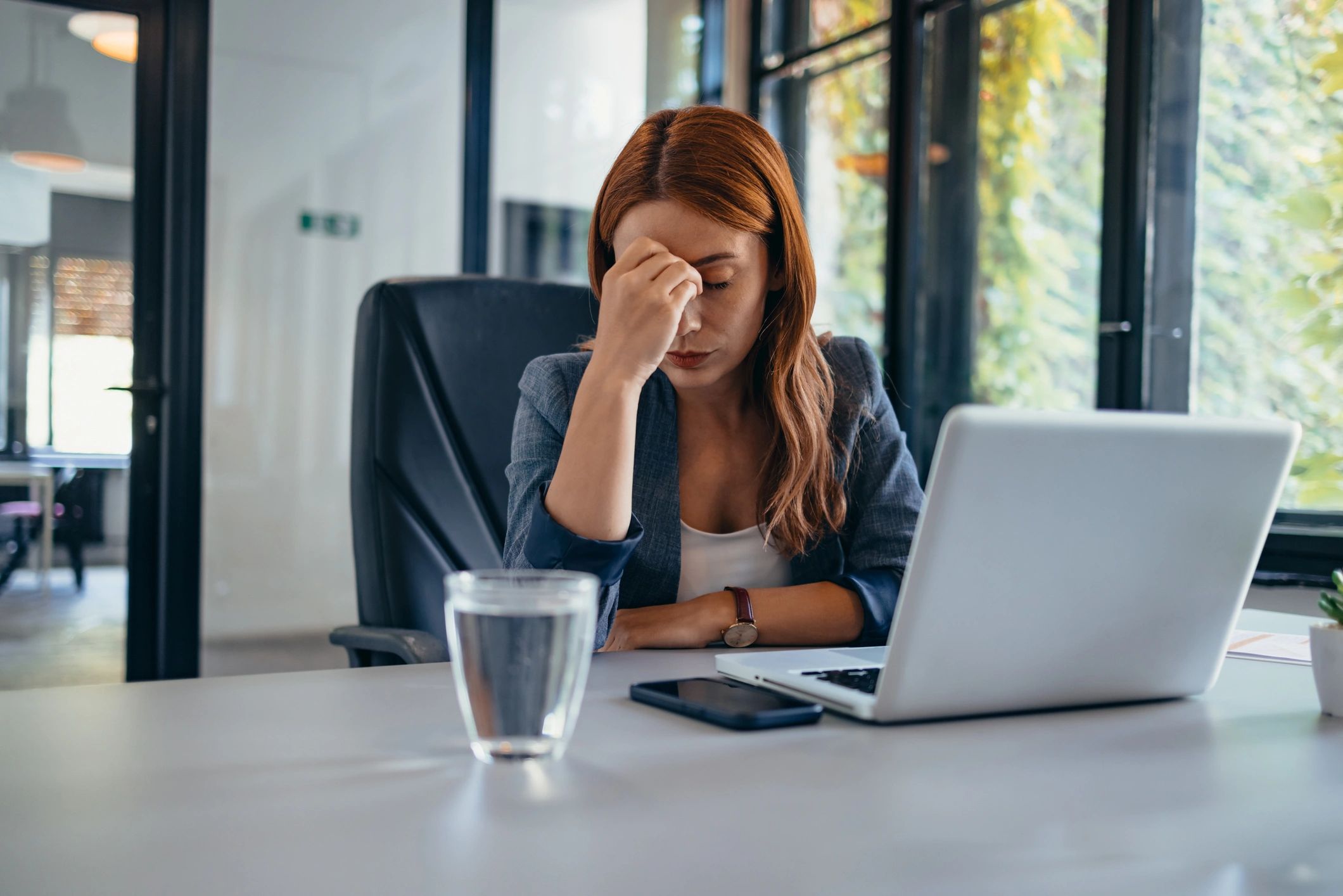 Stressed person at desk overwhelmed by looming deadline in modern office.