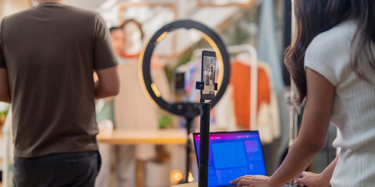 People filming a video with a ring light and smartphone setup indoors.
