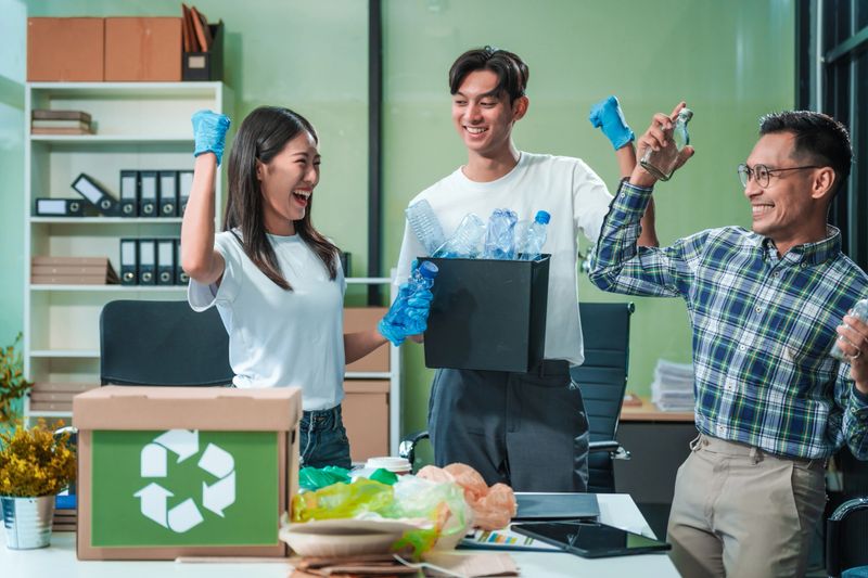 In an office, an Asian team discusses waste management strategies at a desk, separating plastic waste. They explore recycling systems and zero-waste goals to improve environmental sustainability.