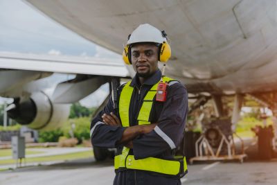 Ground crew member in safety gear near an aircraft.