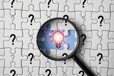 Magnifying glass over puzzle representing finding solutions through solution-focused therapy