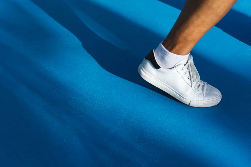 Running on a blue road. The right leg of the man wearing white shoes is on the blue painted concrete floor.