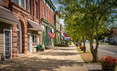 Sunny small-town street with colorful buildings and American flags.