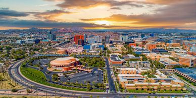 Aerial view of a cityscape with buildings and mountains at sunset.