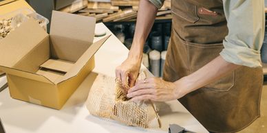 Person packing an item with eco-friendly honeycomb paper inside a cardboard box.