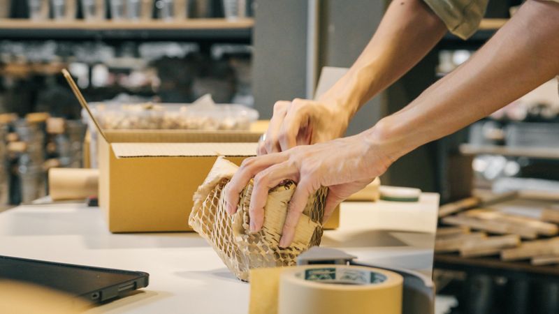 A small business warehouse  worker owner packing eco friendly brown paper honeycomb wrapped with environmental Sustainability friendly paper biodegradable materials before shipping to customers,zero waster and plastic free