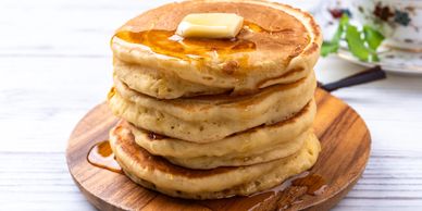 Stack of fluffy pancakes with butter and syrup.