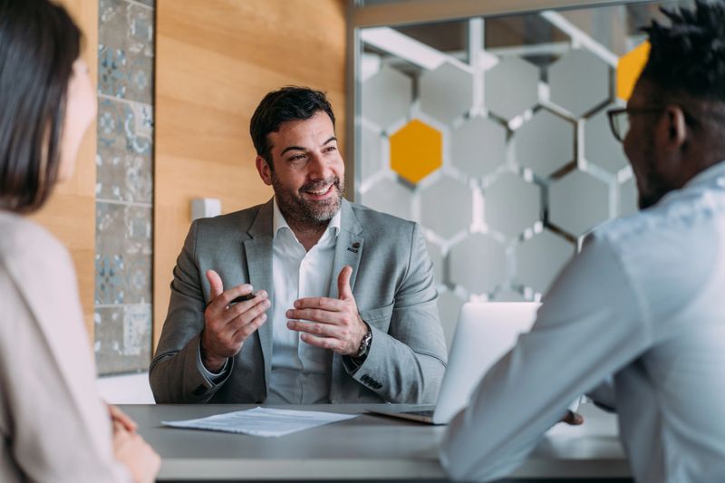 Shot of group of business persons in business meeting. Three entrepreneurs on meeting in board room. Creative business team on meeting in modern office. Male manager discussing new project with his colleagues. Company owner on a meeting with two of his employees in his office.
