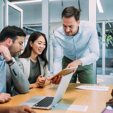 Colleagues collaborating in a modern office around a laptop and tablet.