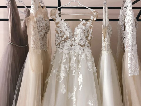 Elegant wedding dresses with lace details hanging on a rack.
