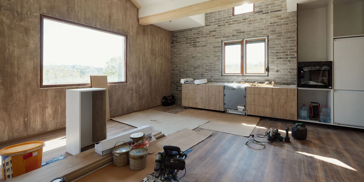 Unfinished kitchen with tools and materials on the wooden floor.
