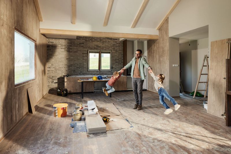 Happy single father having fun while spinning his small kids during renovation process at home.