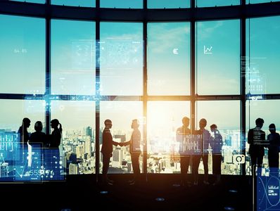 Silhouettes of business people networking in a high-rise office with digital data overlays.