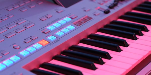 Close-up of a music keyboard with illuminated buttons in blue and red lighting.