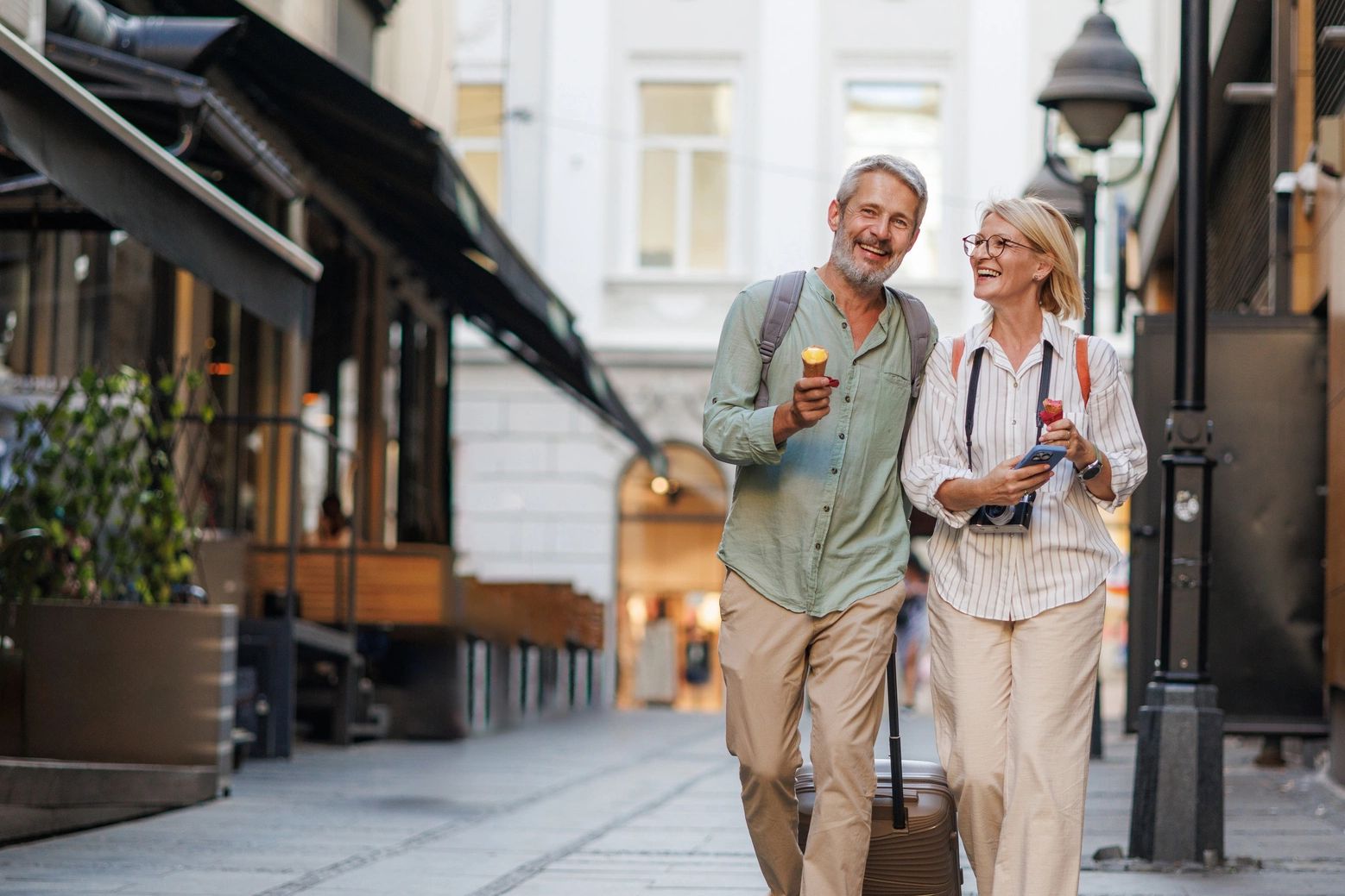 Happy mature couple enjoying living abroad and eating ice cream in a city street where they are grateful for expat resources