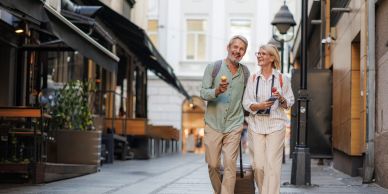 Happy elderly couple walking and enjoying ice cream in a city street.