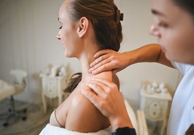 A woman receiving a shoulder massage in a cozy spa setting.
