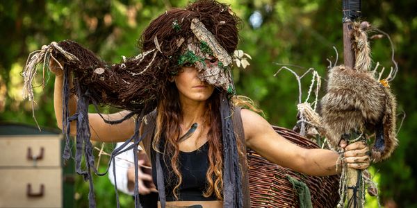 A man dressed in medieval attire stands confidently at a renaissance fair.