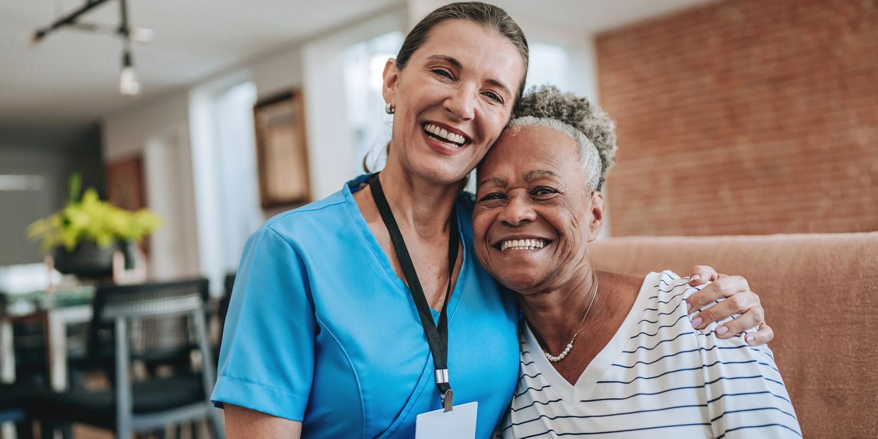 Behavioral health worker smiling and hugging client, providing in-home support and emotional care.