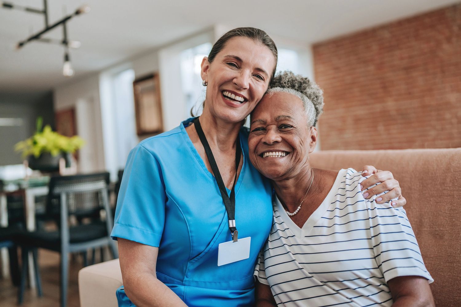 Nurse and elderly woman smiling warmly together at home.
