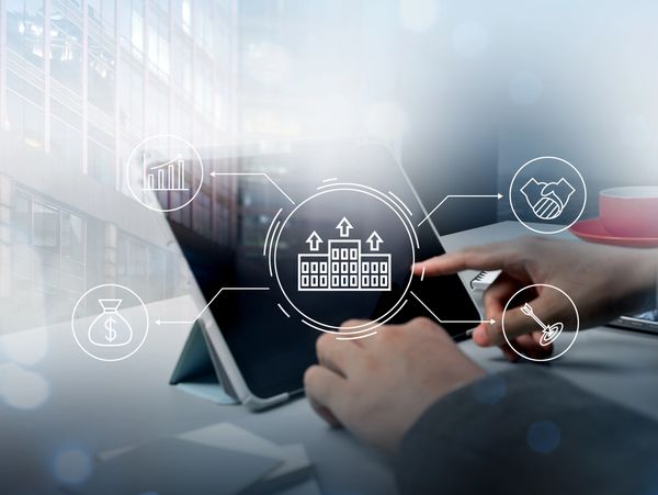Person using tablet with business growth icons overlay.